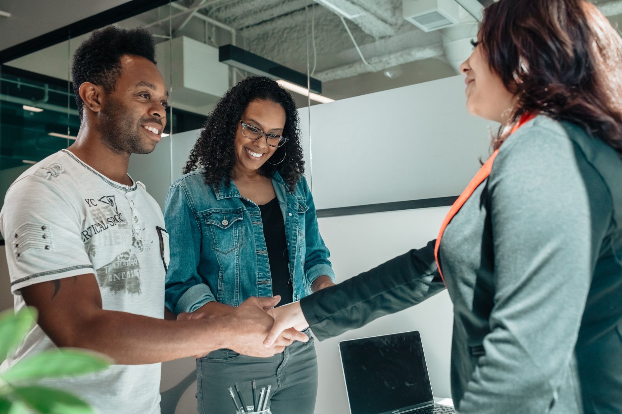 A couple shaking hands with their advisor after a friendly conversation