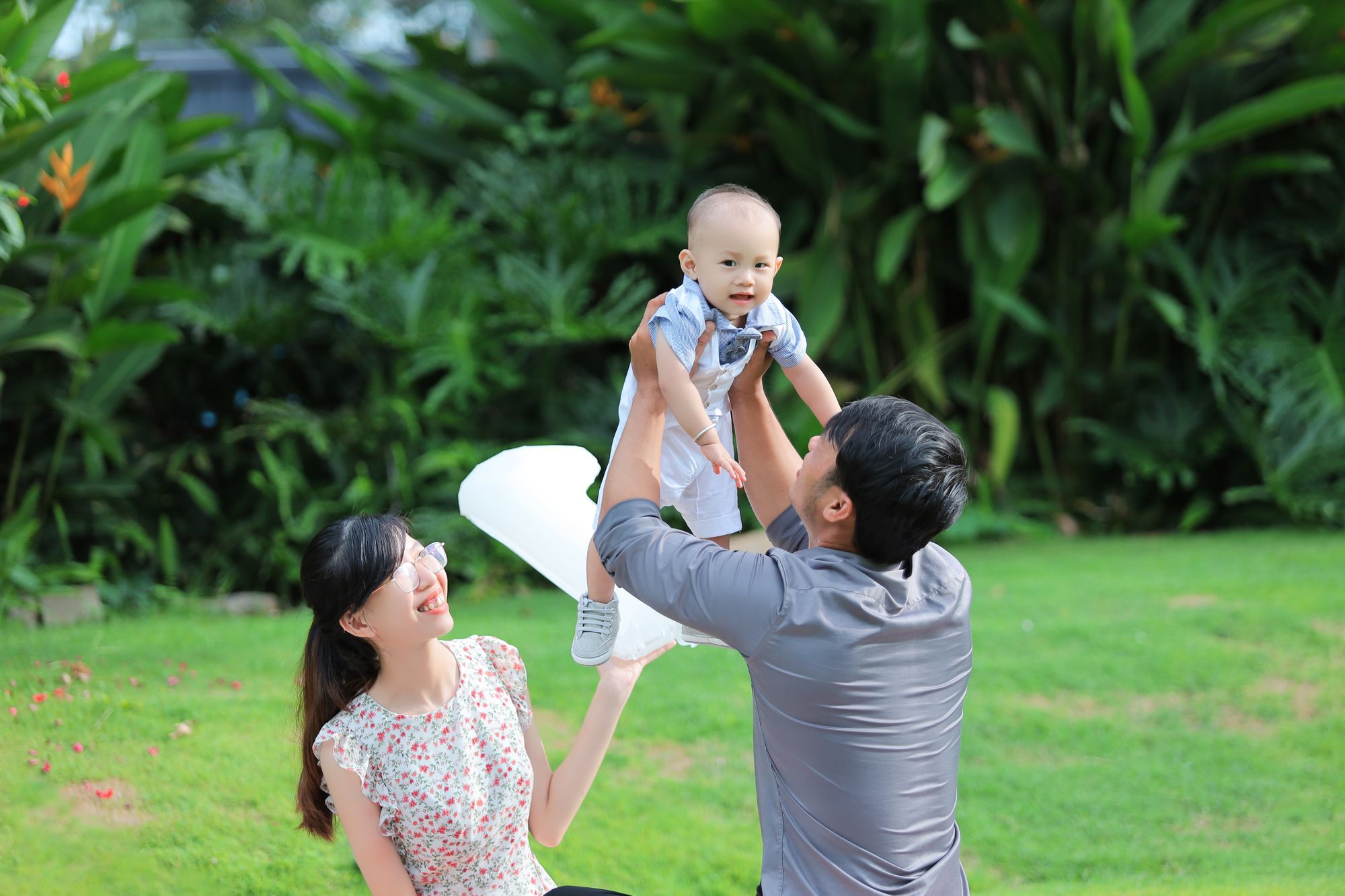Parents joyfully lifting their baby in a sunny park