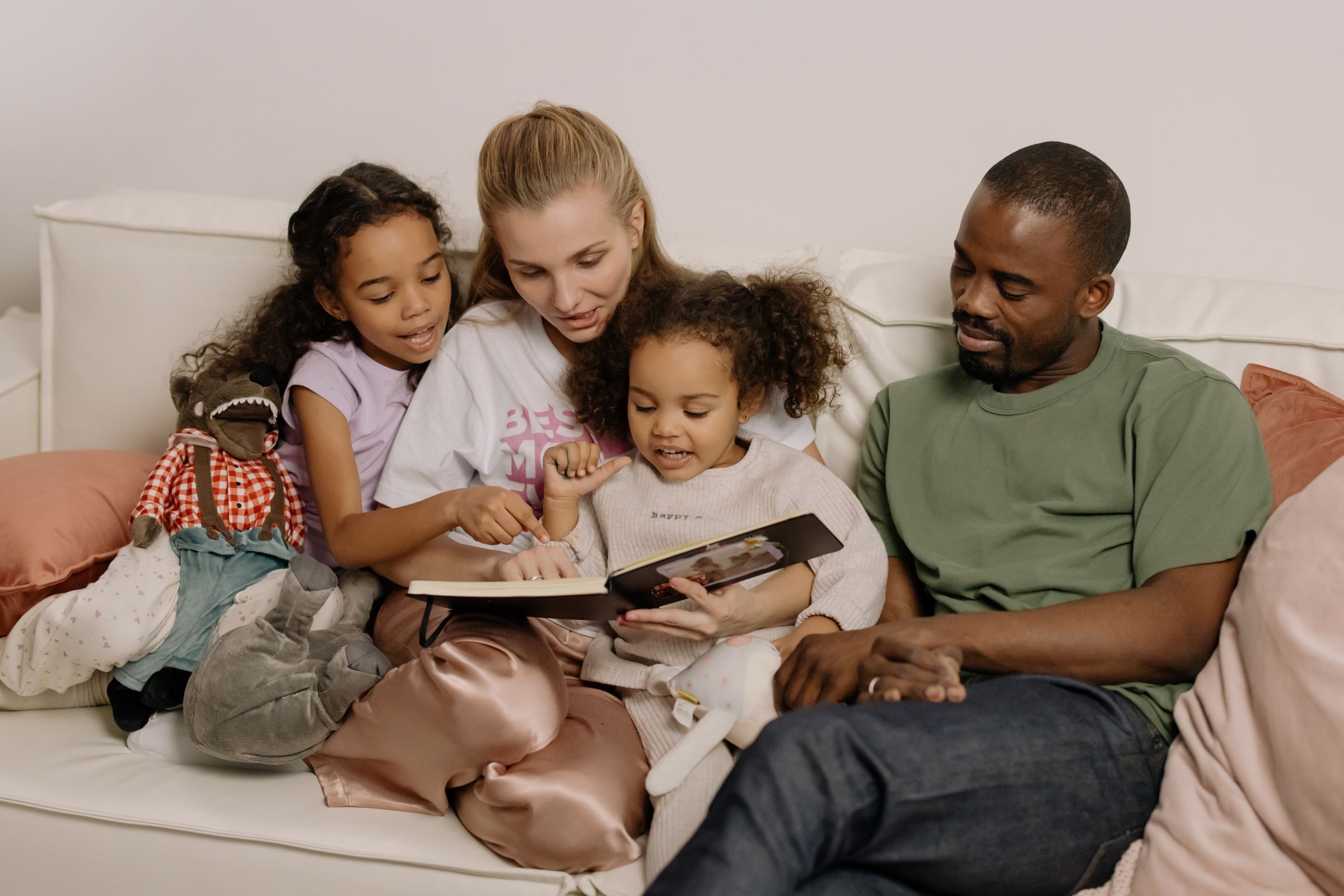 Parents reading a book with their two daughters on the sofa