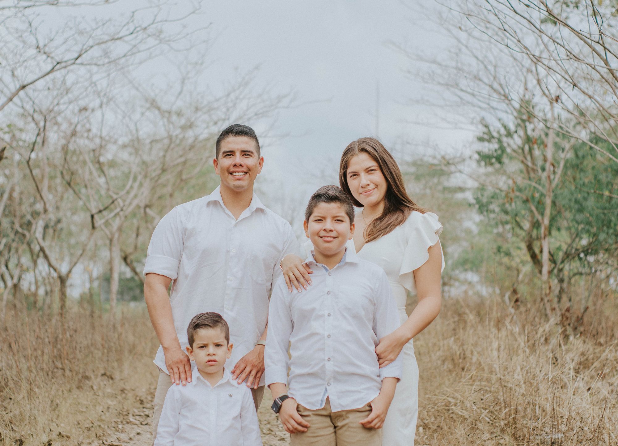 A smiling family of four standing together outdoors
